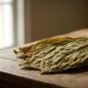Whole cured tobacco leaves on aged oak in soft window light, illustrating the DELIA stick range