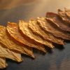 Cured tobacco leaves laid out from pale gold to deep roasted brown, illustrating the TEREA flavour range for IQOS ILUMA